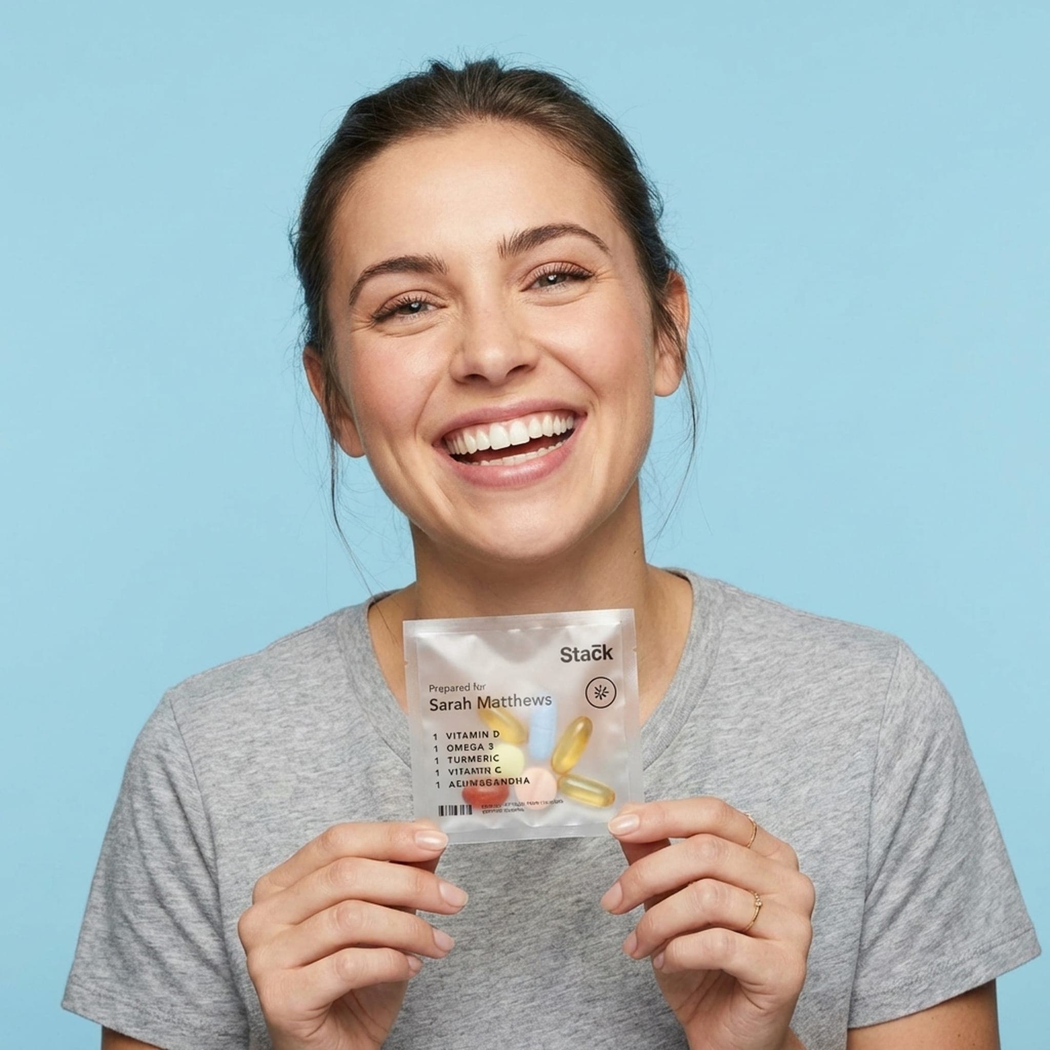 Woman smiling while holding a personalized Stack supplement sachet