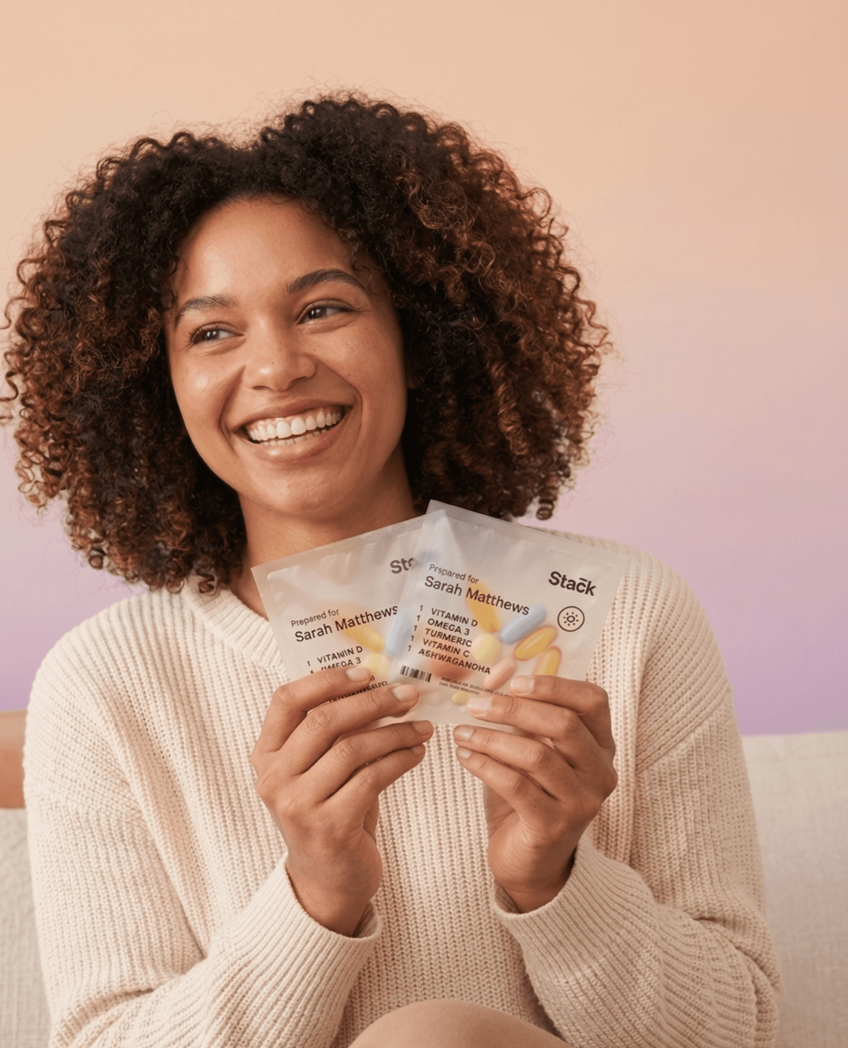 Woman smiling while holding Stack vitamin sachets